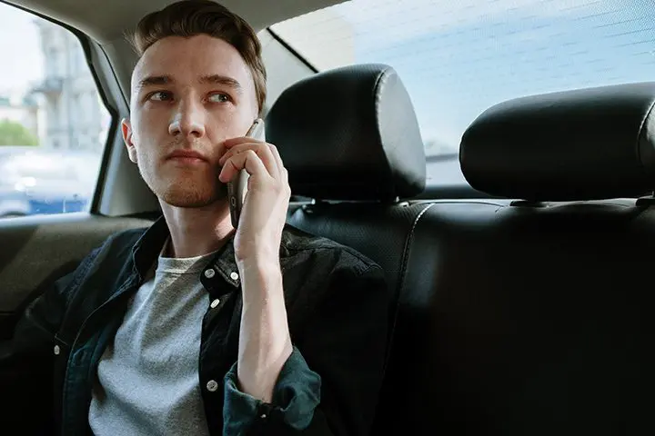 A man sitting in the back of a car talking on his phone.